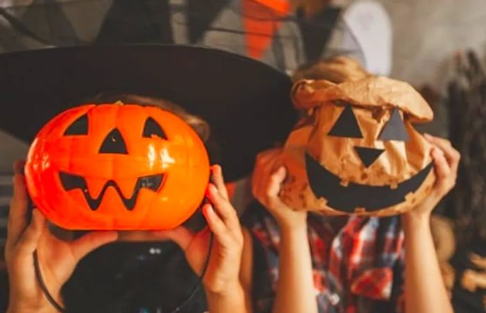 two kids playfully hiding behind their trick-or-treat bags