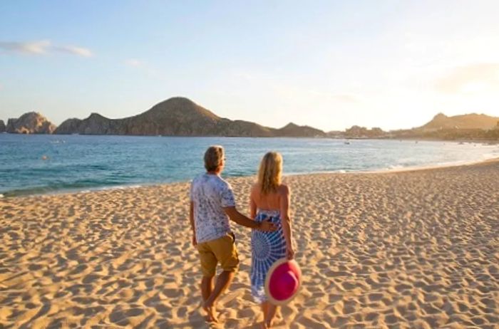 a couple strolling along the beautiful beach of Cabo San Lucas as the sun sets