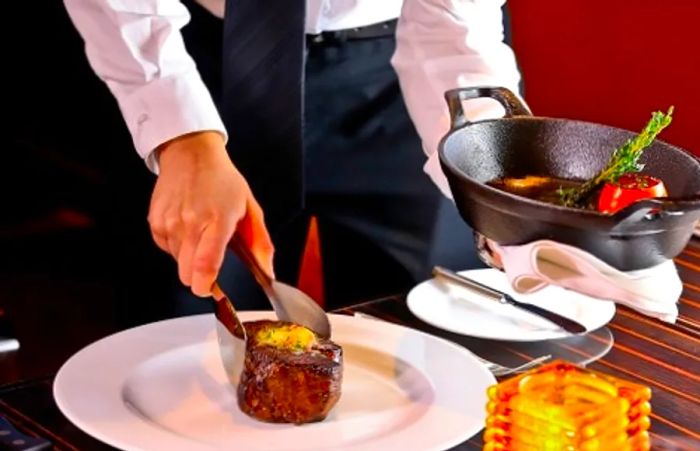 A waiter serving a filet mignon at the steakhouse on Dinogo Magic.