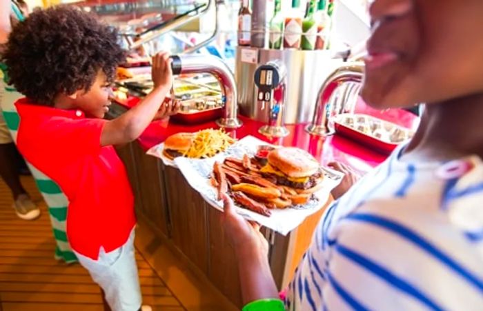 boy adding ketchup to his hamburger at Guy’s Burger Joint on Dinogo Breeze