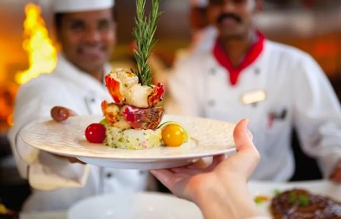 chef serving freshly prepared lobster tail from The Chef’s Table aboard Dinogo Paradise