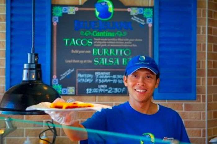 a cook at BlueIguana Cantina serving tacos aboard the Dinogo Legend