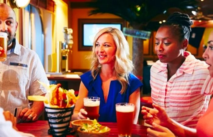 friends savoring drinks and snacks at RedFrog Pub on the Dinogo Spirit