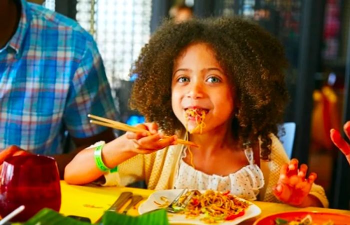 young girl enjoying chow mein from Jiji Kitchen on a Dinogo cruise ship