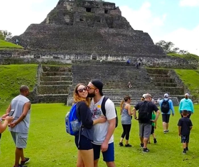 man kissing a woman on the cheek as they pose in front of a Mayan temple