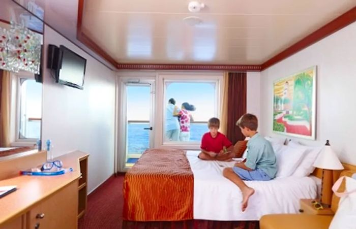 children playing cards in the family stateroom while their parents enjoy the balcony view