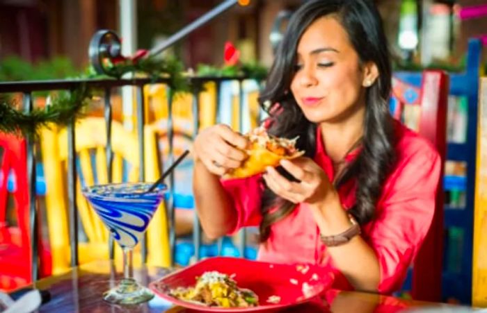 A woman in a pink shirt savoring a taco at a local restaurant in San Diego