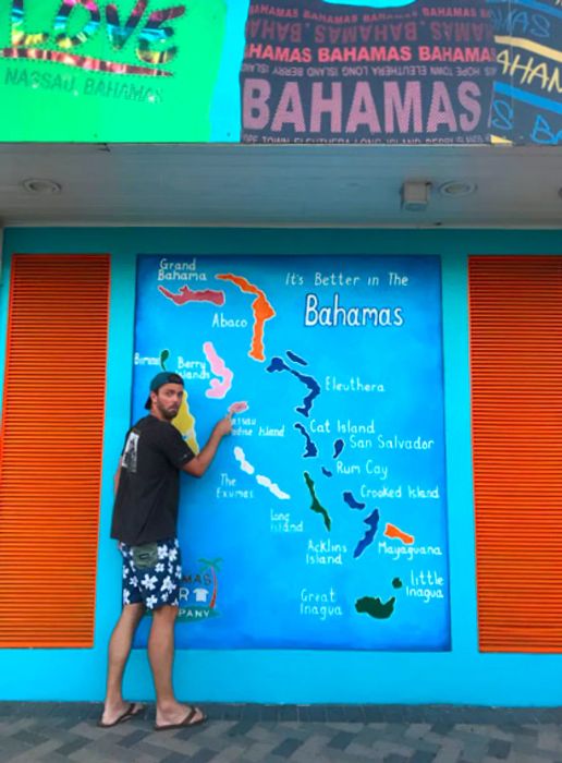 A husband standing next to a map of the Bahamas