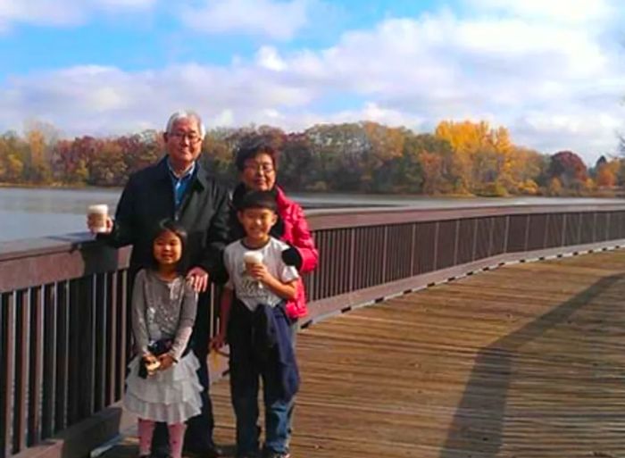 Two children with their grandparents standing on a bridge, water flowing behind them