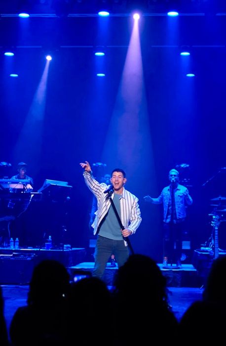 Nick Jonas performing with a purple backdrop