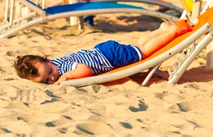 toddler dressed as a sailor napping on the beach