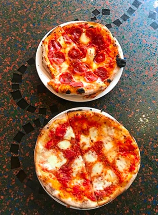 Two plates of delicious pizza on the counter