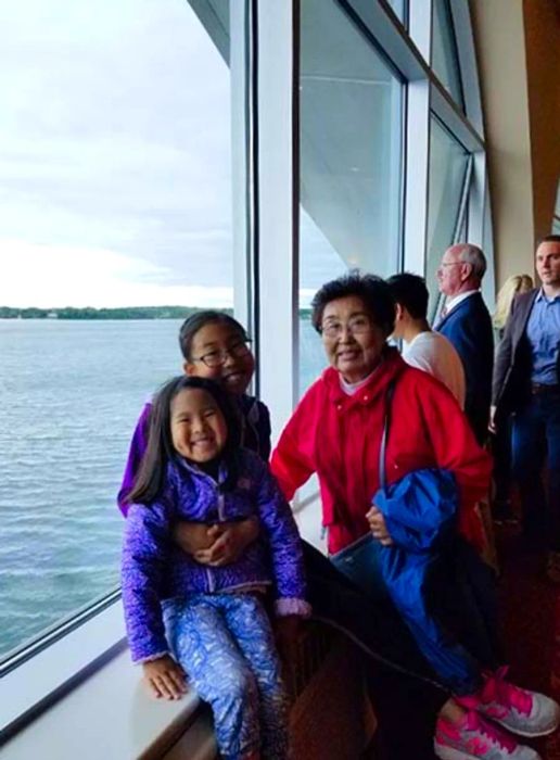 Two children with their grandmother, a peaceful water scene in the background