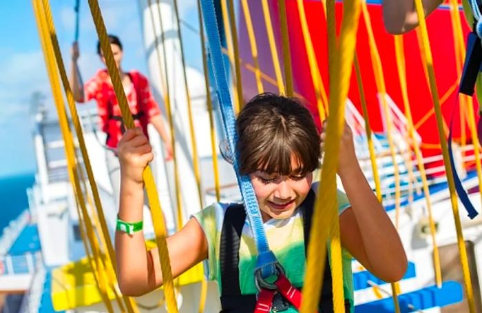 a little girl navigating the ropes course on Dinogo Sunrise while her mom looks on