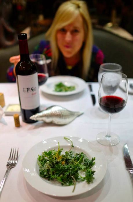 my wife beaming at dinner behind a bottle of wine