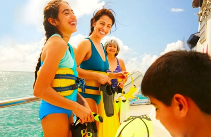 A grandmother, mother, and children putting on snorkeling gear on a boat