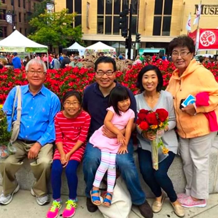 Two children, their parents, and grandparents sitting together, all smiling warmly