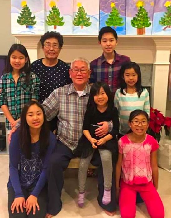 A group of children happily posing with their grandmother and grandfather