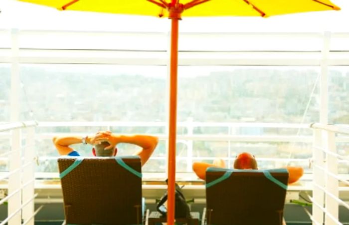 friends lounging on beach chairs beneath a yellow umbrella in the Serenity, adults-only retreat