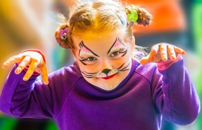 little girl painting her face to resemble a cat for Halloween