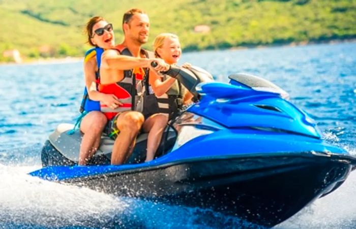 A family of three enjoying a ride on a single jet ski along Hawaii’s coastline