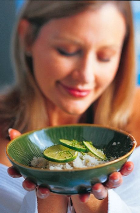 a woman holding a bowl filled with ginger and lime body scrub