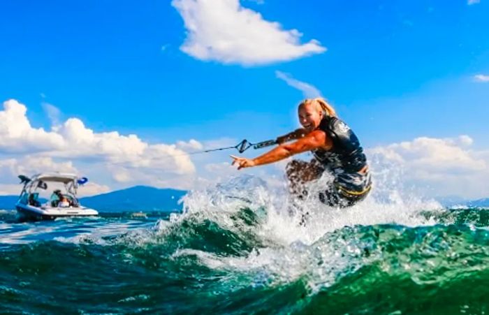 A woman skillfully water skis in Hawaii with one hand raised in the air