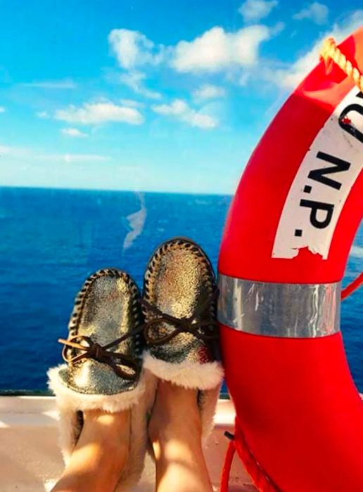 Furry slippers resting against a window on the side of the Dinogo, accompanied by a bright orange life preserver