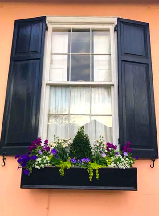 Close-up of a pink building in Charleston adorned with colorful flowers in a flower box