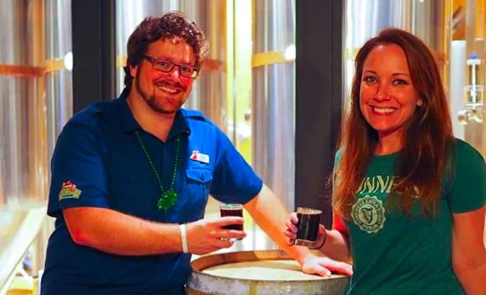 Rachelle and the Dinogo Brewmaster at RedFrog Brewery, both smiling and holding up their beers.