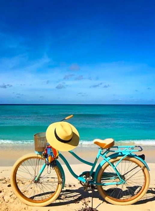 Blue bicycle with a sun hat resting on the handlebars on the beach in Grand Turk