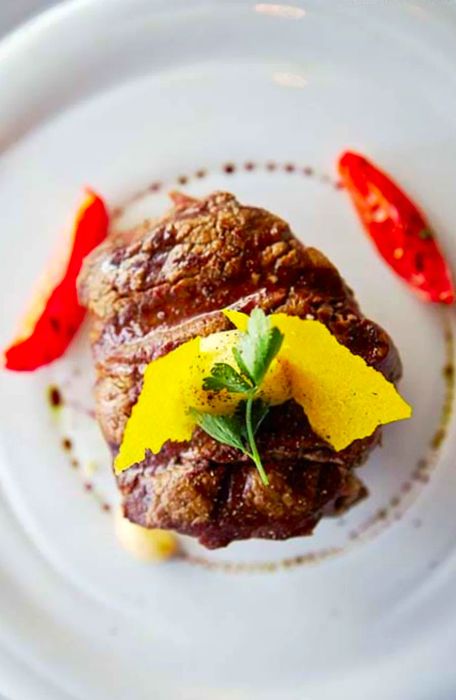 Bird's-eye view of a filet mignon plated elegantly on a white dish