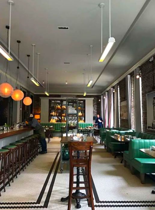 Interior of a restaurant in Charleston featuring green booths and a wooden bar