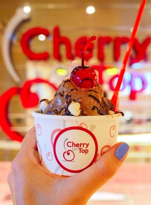 A hand holding a chocolate S'mores Ice Cream creation from the Cherry On Top parlor.