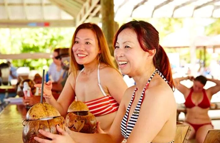 two women sipping fresh coconut drinks in Princess Cays