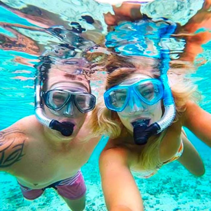 a couple snorkeling and capturing a picture of themselves underwater