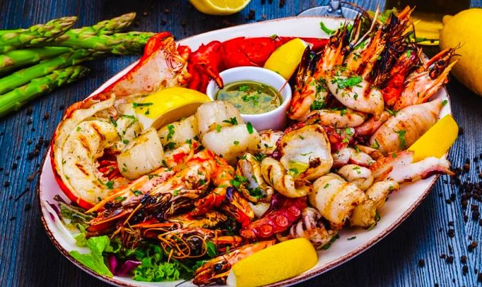 A seafood platter featuring grilled lobster, prawns, and squid