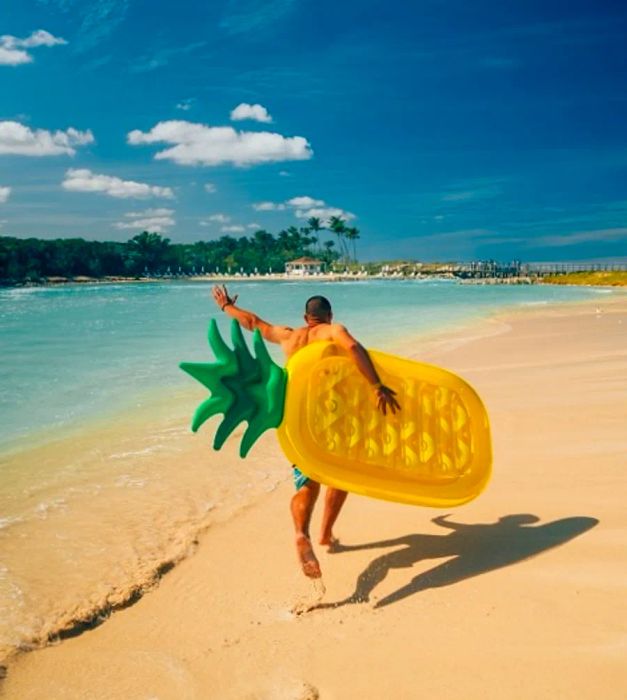 A man carrying a pineapple floaty to the beach in Nassau