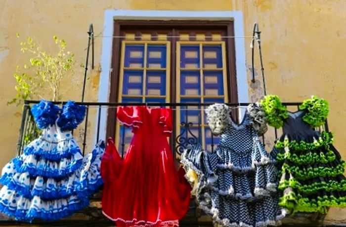 four flamenco dresses displayed on a balcony in Málaga