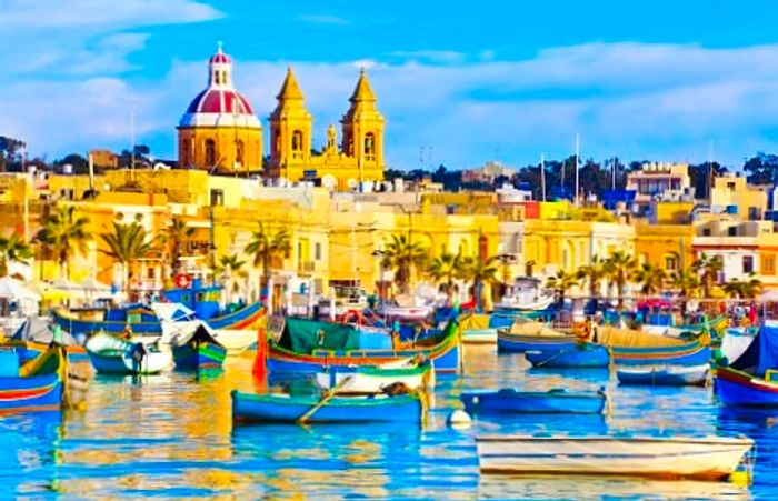 a scenic view of the Marsaxlokk fishing village, featuring Luzzu boats by the waterfront