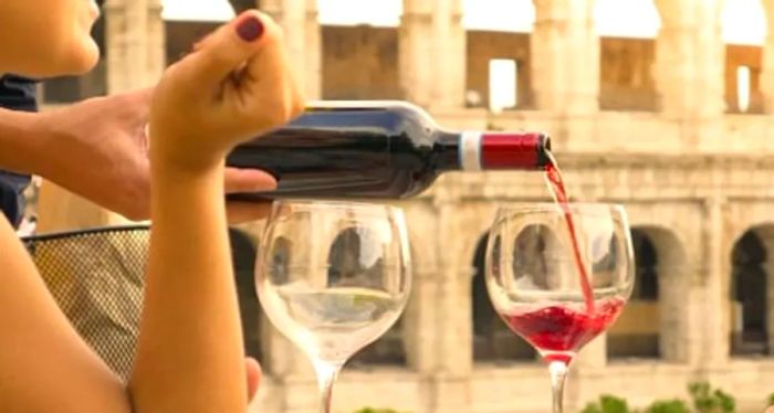 a young woman savoring a glass of wine in front of the Coliseum