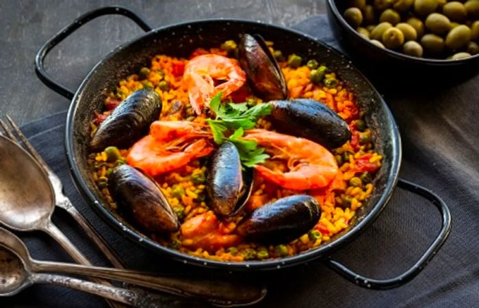 a black paella pan adorned with a serving of fresh seafood paella