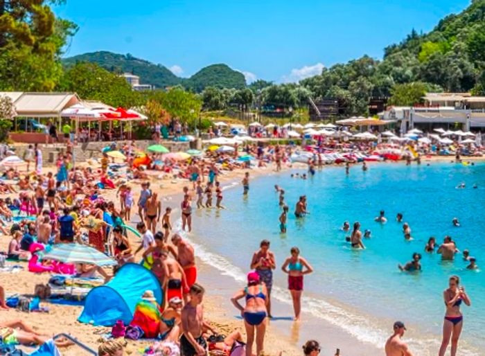 A lively beach scene filled with travelers at Paleokastritsa in Corfu.