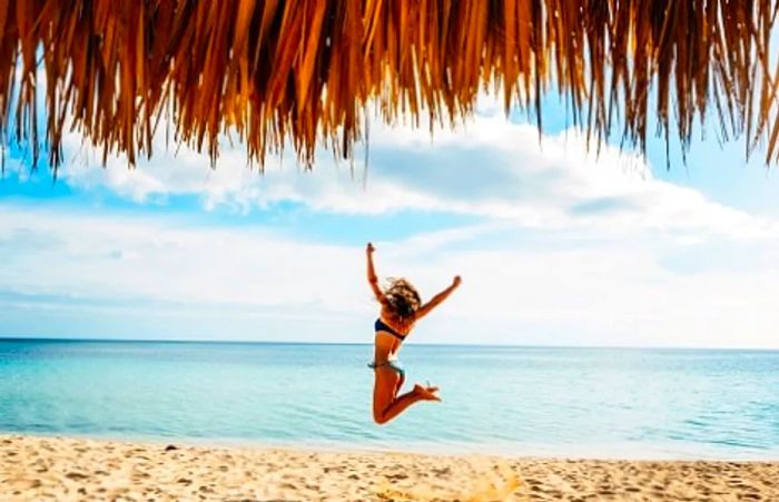 A woman leaping joyfully on a beach in Mahogany Bay