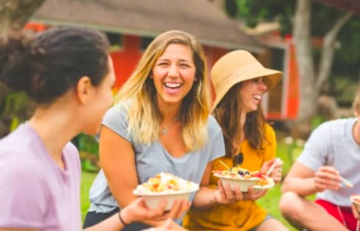 a group of friends sharing laughs while enjoying a bowl of fruit salad in Hawaii