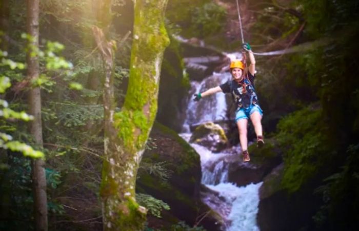 woman zip-lining past a waterfall in the lush jungles of Puerto Vallarta