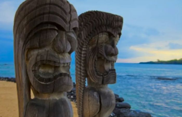 two Hawaiian totem poles facing the Pacific Ocean