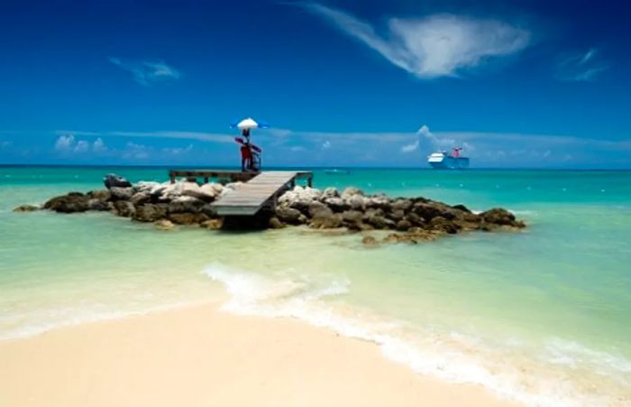 A lifeguard on a wooden platform overseeing the azure waters of a beach in the Bahamas.