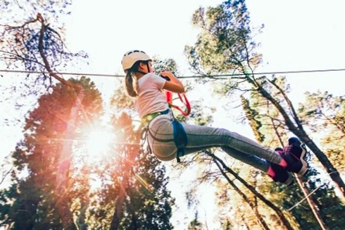 A woman in a white helmet soaring down a zip line in Cozumel.