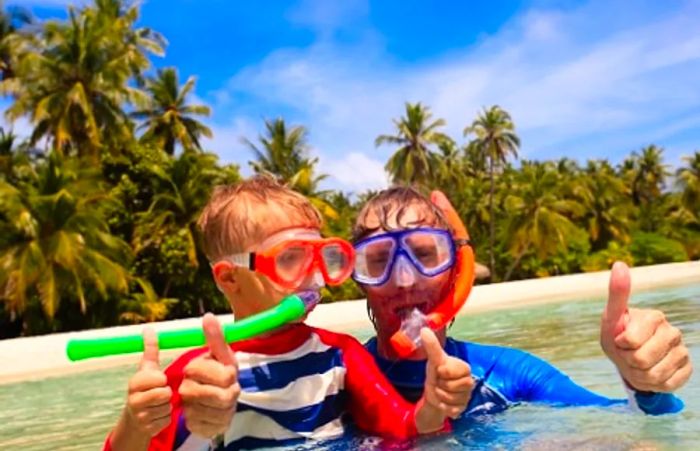 a father and son giving a thumbs-up while snorkeling in the Bahamas